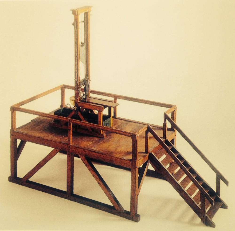 Instruktionsmodell der Guillotine mit Schafott, Abschrankung und Treppe (HMLU 2980). Die Holzkiste zur Aufnahme des Leichnams ist unter den Tisch eingeschoben