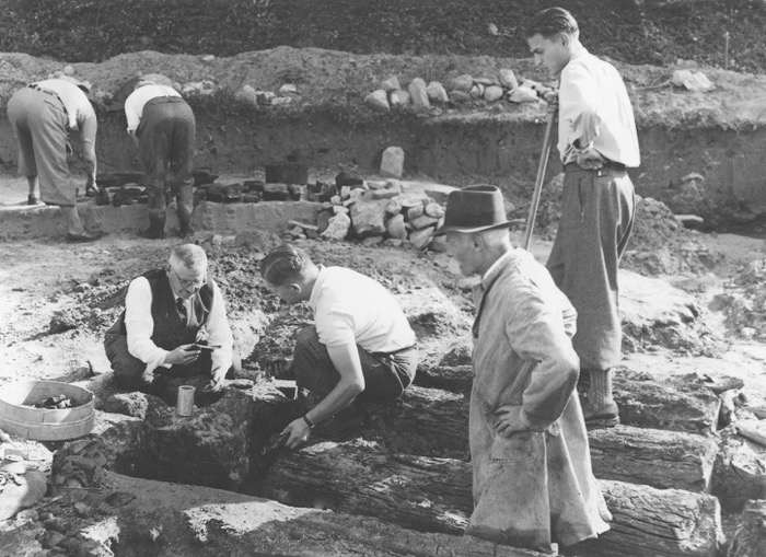 Während der Ausgrabung der römischen Mühle von Cham-Hagendorn in den Jahren 1944/45. Ausgrabungsleiter Josef Speck und Albert Weiss sowie freiwillige Helfer legen die noch gut erhaltenen Hölzer frei.