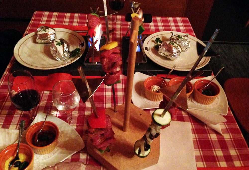 Ein Blattsalat, drei Spiesse, eine Ofenkartoffel und verschiedene Saucen gehören zum Tisch-Cheminée.