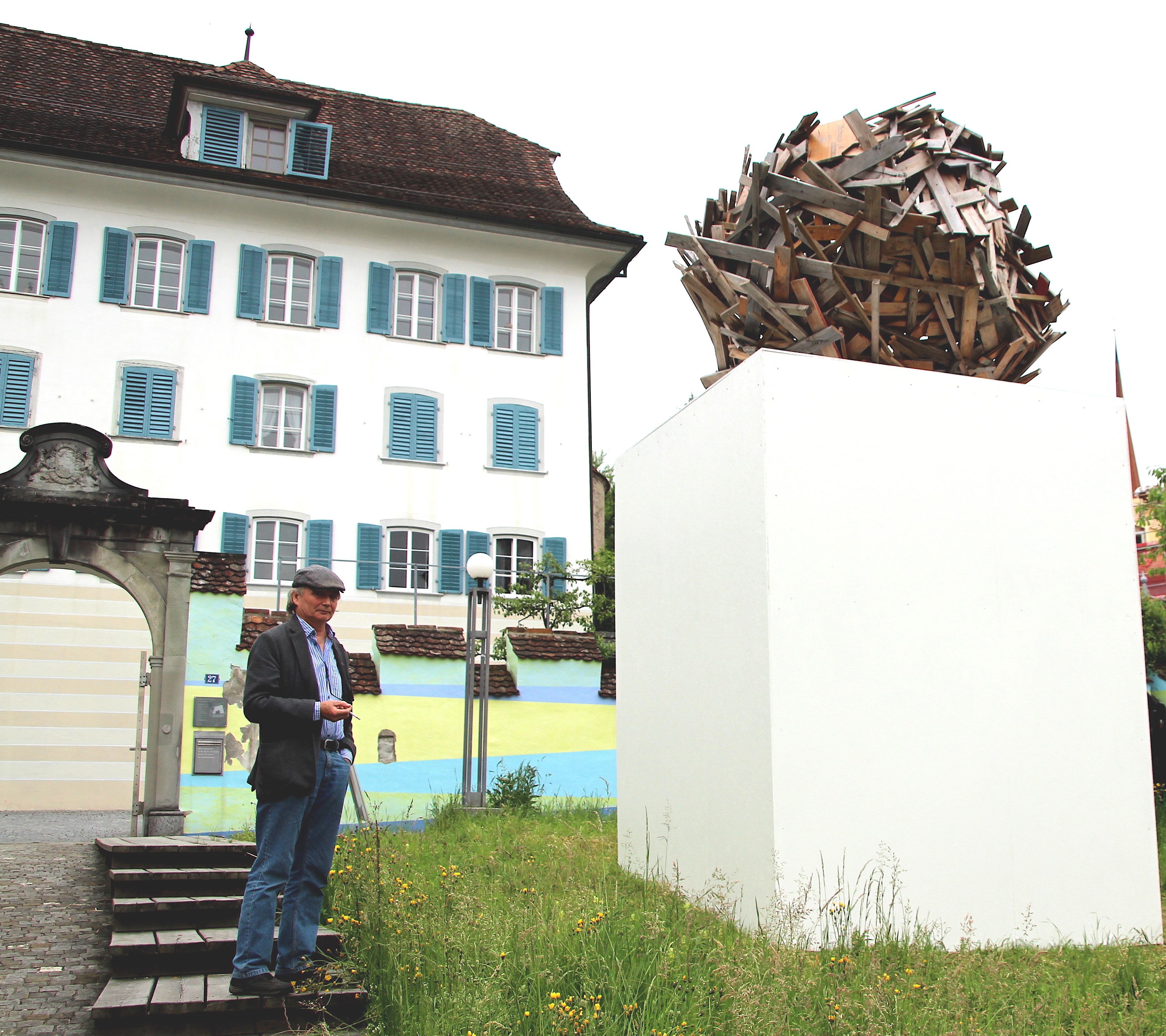 Der Künstler Christoph Rütimann neben seiner Installation aus Nägeln und Brettern. Er will sich dort einigeln.