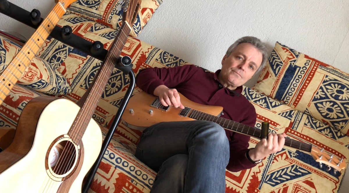 Richard Koechli zu Hause auf seinem Sofa, in der Hand eine Luzerner Relish-Gitarre.